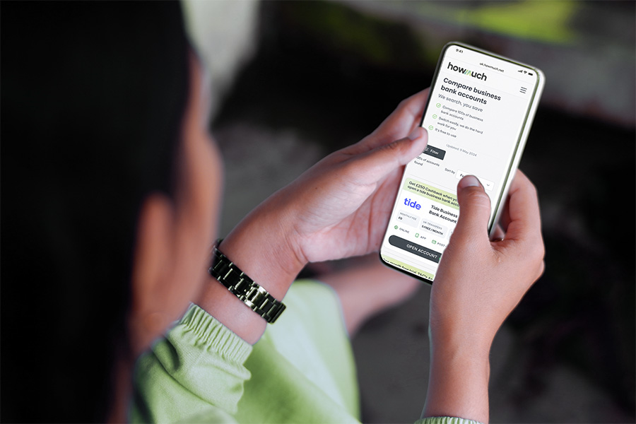 A person comparing business bank accounts on HowMuch using their phone